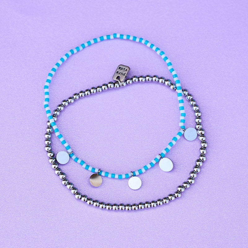 Both bracelets from the silver set are laying on a flat surface. They are a stretch, pull on design.