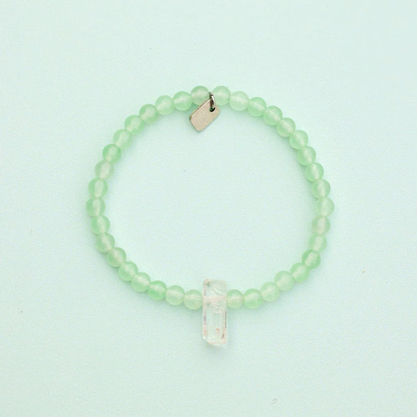 Shows bracelet on a flat surface. Green quartz beads with raw clear quartz center crystal.