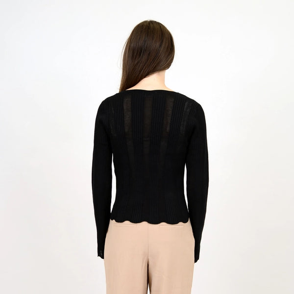 back view of the model wearing the medellin long sleeve v neck pullover. shows the scalloped bottom hem. also shows the fitted style and the sheer lines throughout. 