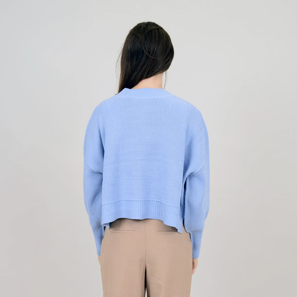 back view of the model wearing the sumire cardigan. shows the side slits. also shows the ribbed heming and the dropped shoulders.