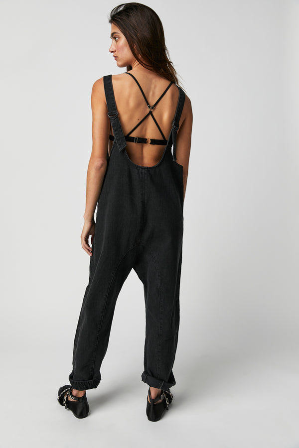 Back view of model wearing jumpsuit. Shows the low back with adjustable straps. Also shows the low crotch harem style pants, ankle length and the beautiful mineral wash black. 