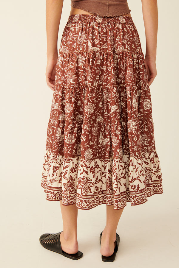 back view of model wearing the full swing printed midi skirt. shows the beautiful printed floral design. also shows the mid length, the flowy fit and the stretchy waistband. 