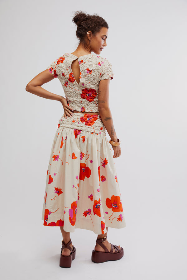 back view of the model wearing the carino printed set. shows the keyhole in the back on the top. the smocking throughout the whole top and the top of the skirt. also shows the midi length of the skirt. 