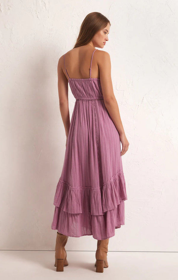 back view of the model wearing the rose maxi dress. shows the elastic waistband. also shows the adjustable straps, the bottom tiered ruffles and the maxi length. 