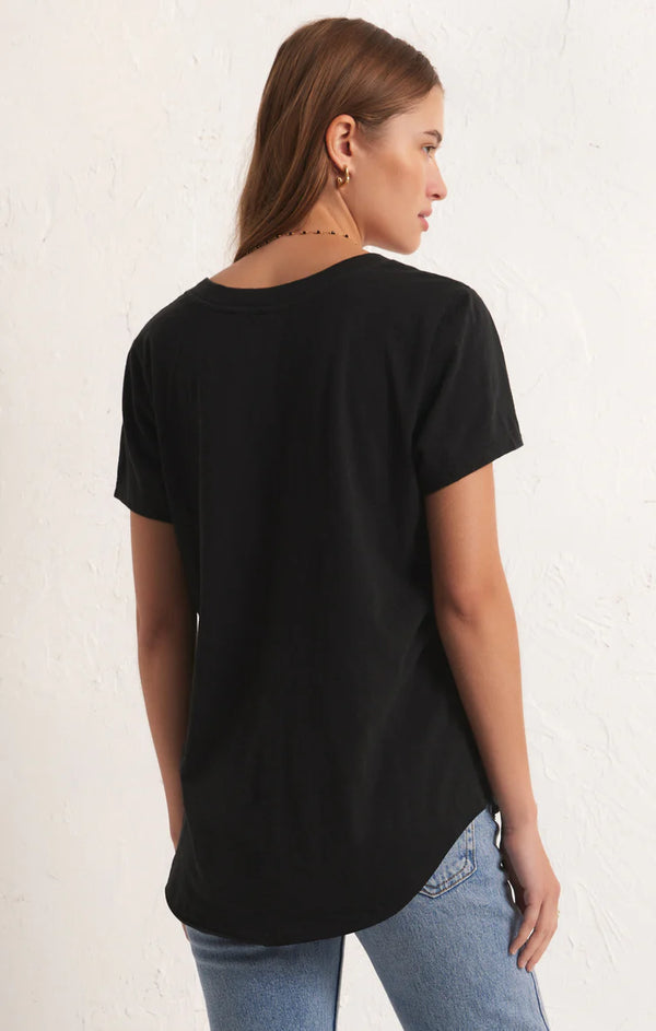 back view of the model wearing the asher v neck tee in black. shows the curved bottom hem. also shows the shorts sleeves and relaxed fit. 