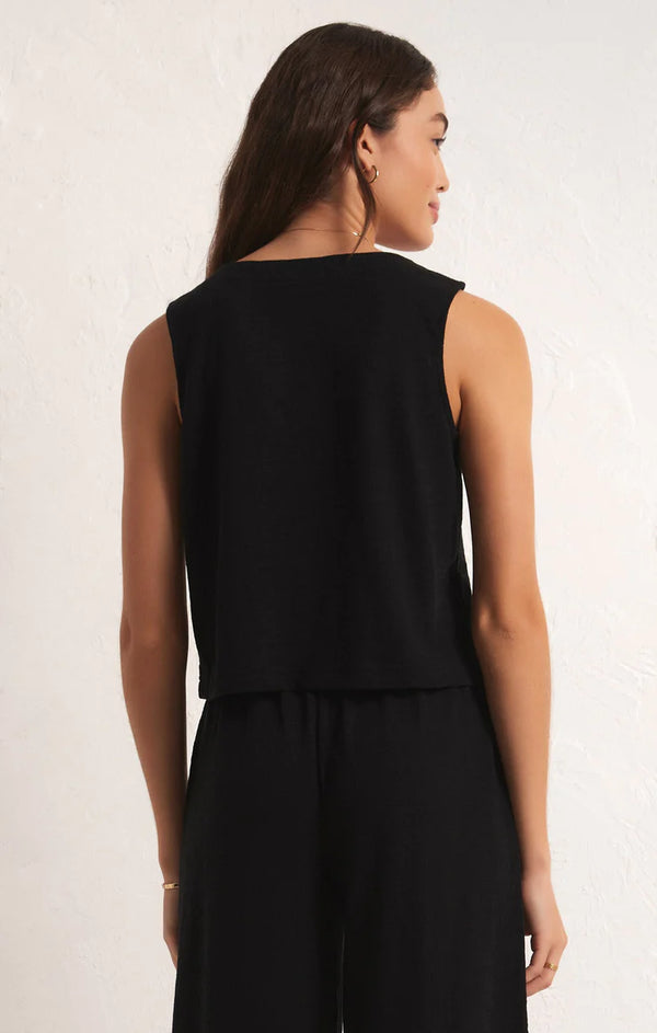 back view of the model wearing the solace textured slub top in black. shows the relaxed fit. also shows that the top is sleeveless and waist length. 