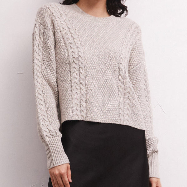 front view of the eternal sweater in dove. shows the cable knit detailing. also shows the drop shoulders, the blouson sleeves, the crew neckline and the ribbed detailing on the cuffs and neckline.