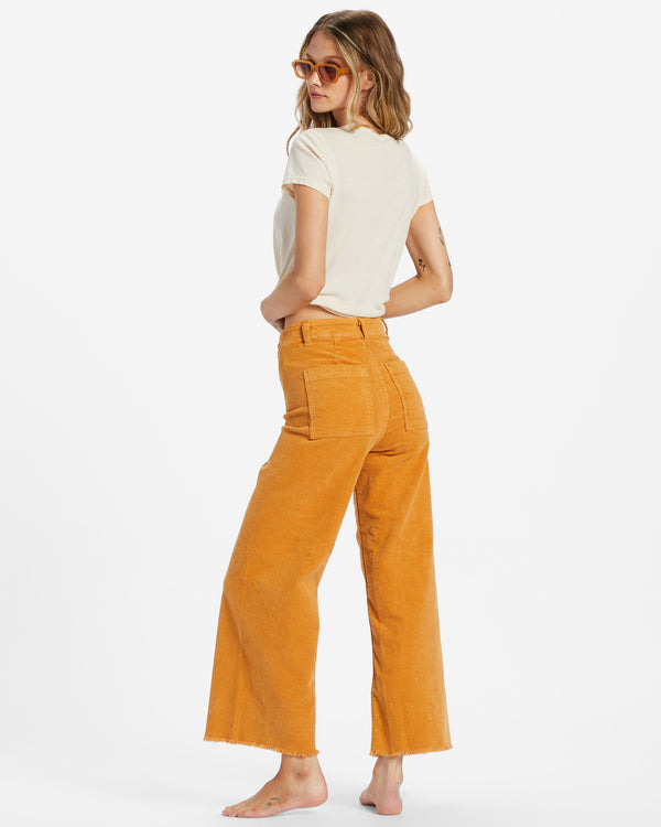 back view of model wearing the free fall pants in golden rays. shows the back square pockets. also shows the frayed raw hem, and the belt loops.