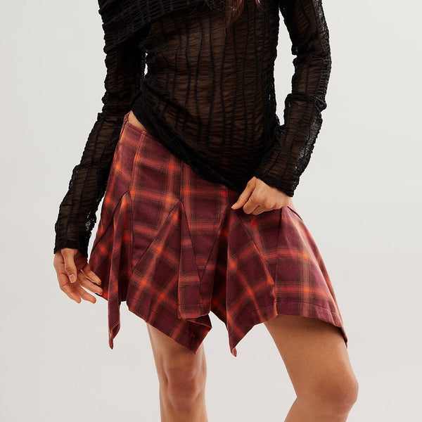 front view of model wearing the XIA plaid mini skirt in burgundy. shows the mid-rise fit. also shows the asymmetrical pleating and the plaid detail throughout. 