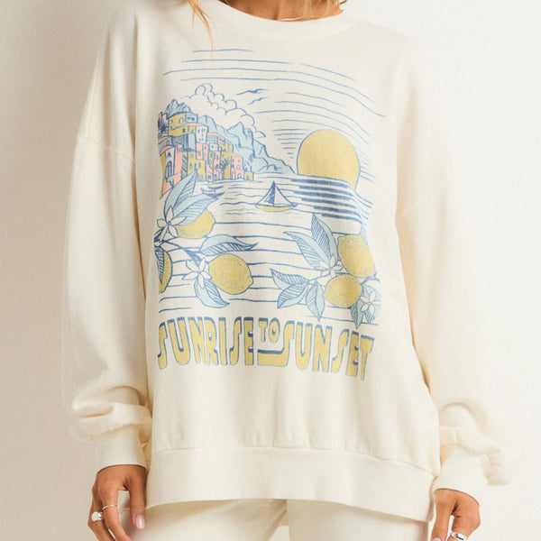 front view of the model wearing the sunrise sunday sweatshirt. shows the crew neckline. also shows the front screen print, the oversized fit and the dropped shoulders.