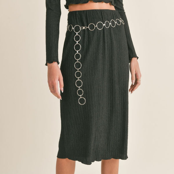 front view of the Nelly midi skirt in black. shows the elastic waistband. also shows the lettuce trim hem, the midi length, and the ribbed detail.