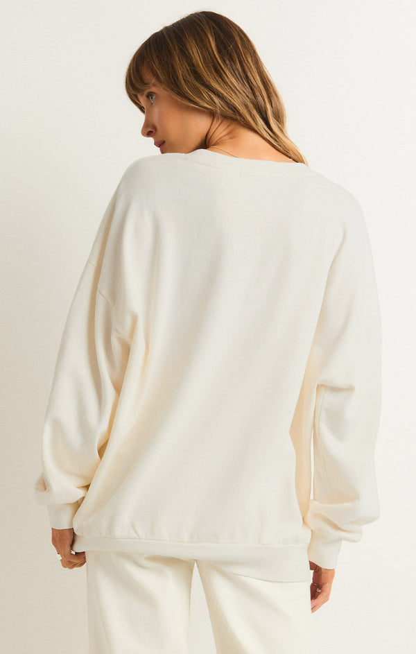 back view of the model wearing the sunrise sunday sweatshirt. shows the crew neckline. also shows the dropped shoulders and the oversized fit. 