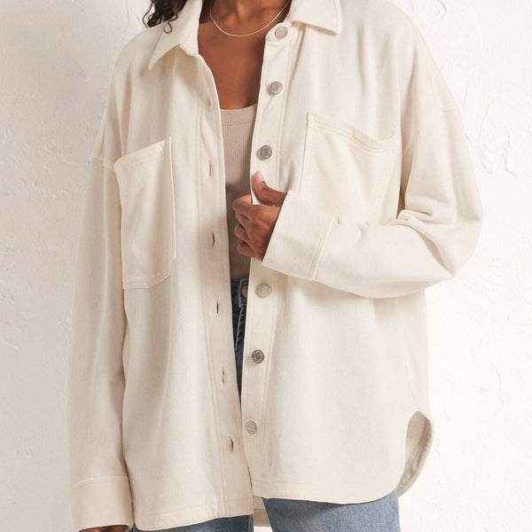 front view of the model wearing the all day knit jacket. shows the bottom curved hem. also shows the two front pockets, the button down closure and the traditional collar.