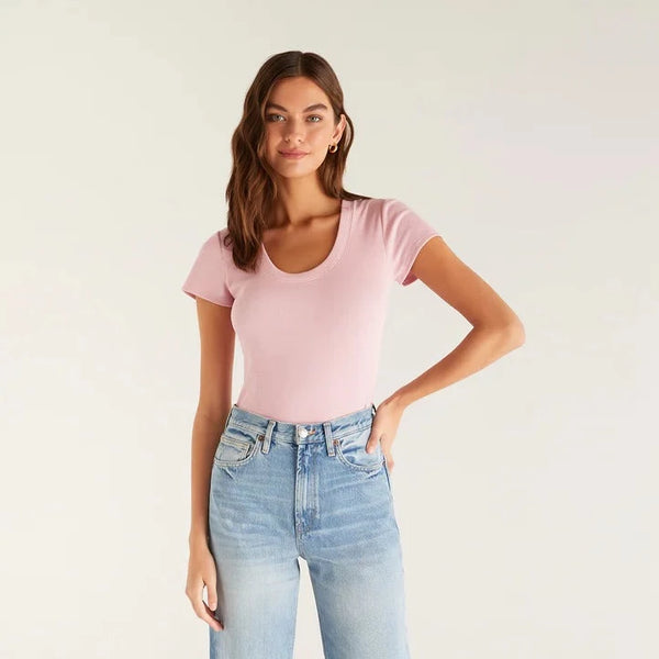 Front view of pink top. Model is wearing it tucked in. Shows a fitted silhouette with scoop neckine, ribbed fabrication and short sleeves.