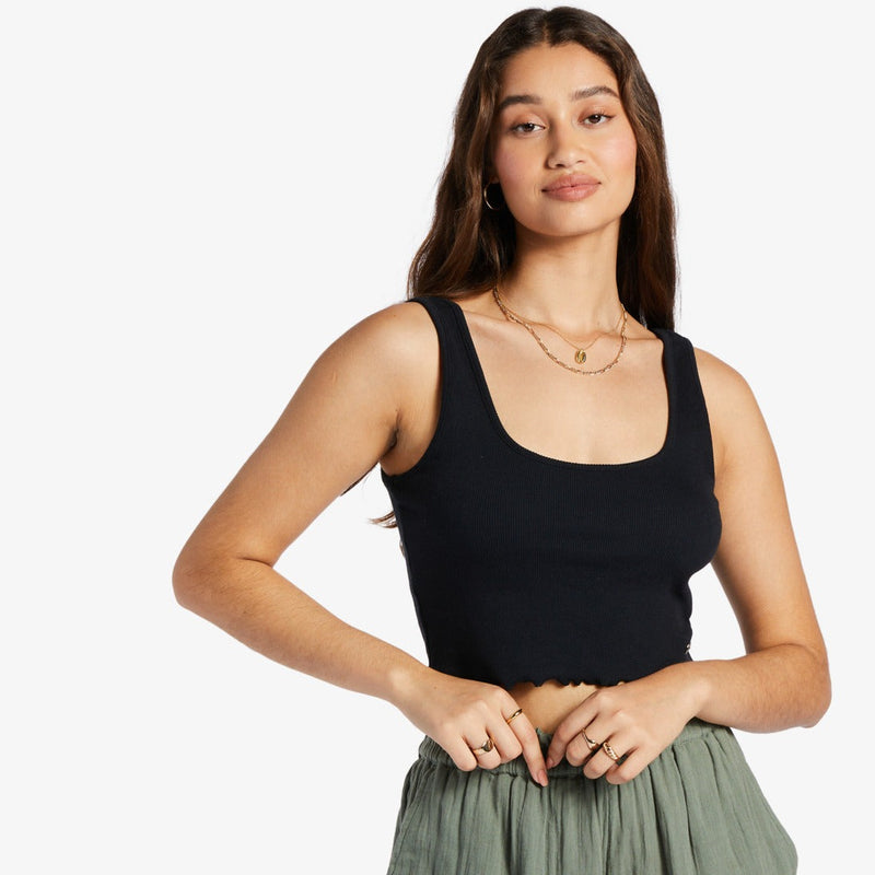 shows front view of model in the black tank. shows the scoop neckline, ribbed fabrication and lettuce edge hemline. hit model above the belly button.