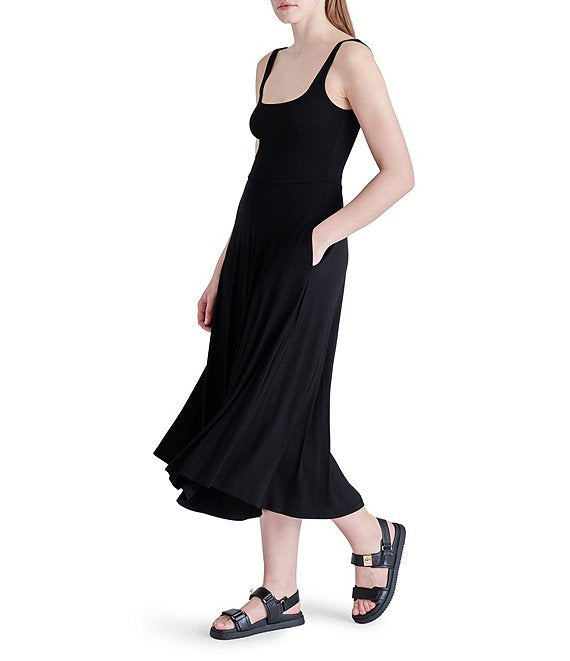 shows an angled side view of the dress. models hand is in the side pocket and you can see the flowy skirt, hits model at mid calf.