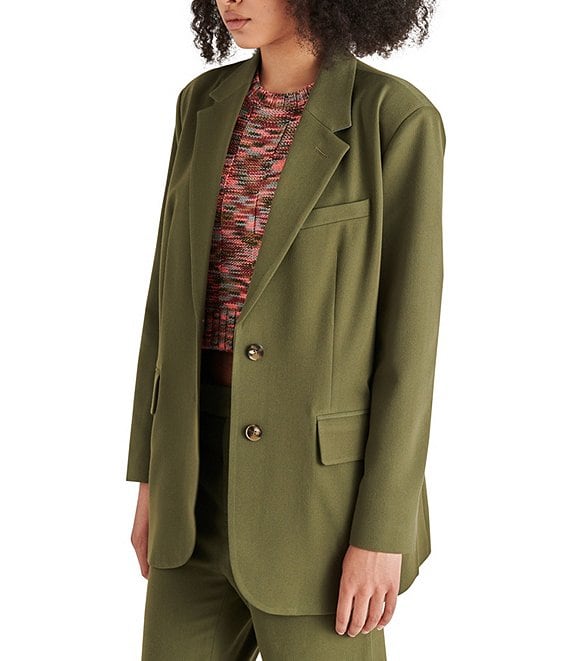angled side view of model in blazer. shows the lapel collar, oversized fit, two buttons down the front, and not detail down the front.