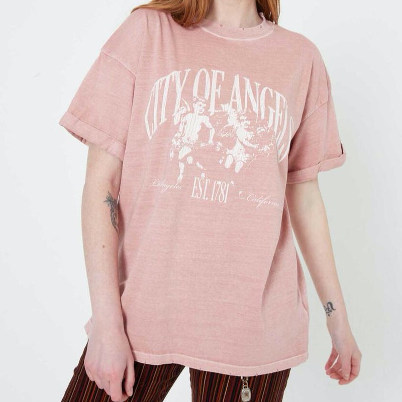 Front view of model wearing tee. Shows the cuffed sleeves. Also shows the oversized fit, the vintage look and the distressing on the neckline and bottom hem. 