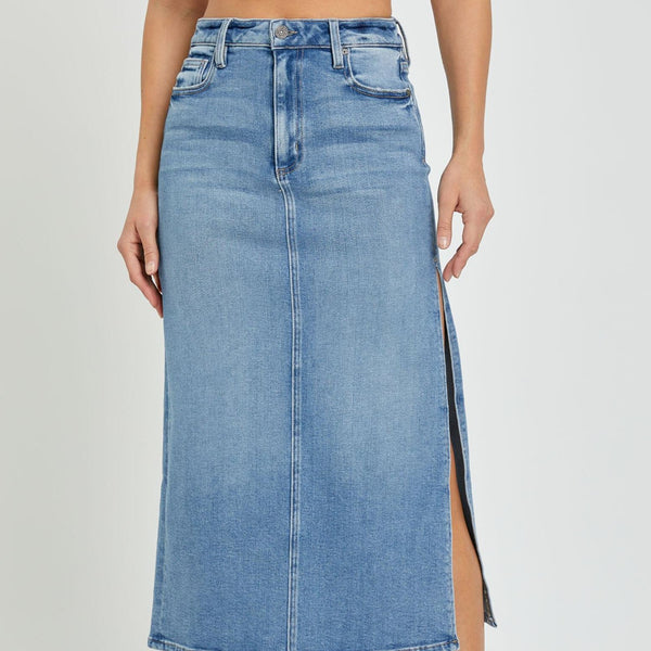 front view of the model wearing the peyton midi skirt. shows the side slit. also shows the seam going down the front of the skirt, the button closure and the standard pockets. 