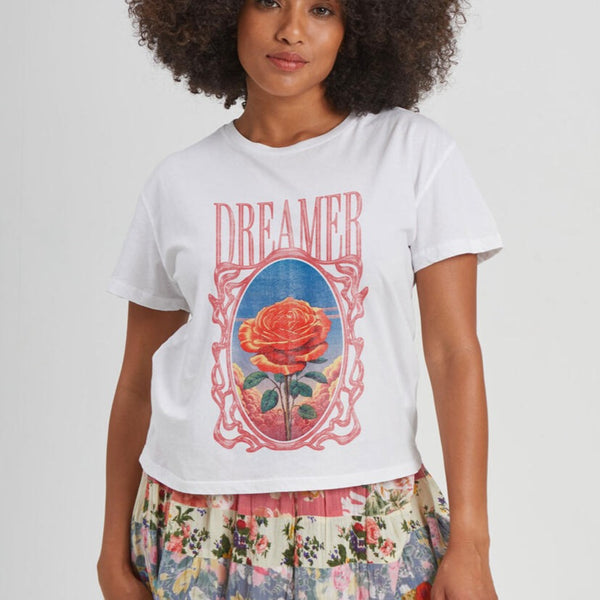 front view of the model wearing the dreamer t shirt. shows the crew neckline. also shows the short sleeves, the slight cropped length and the front graphic that says DREAMER with a rose. 