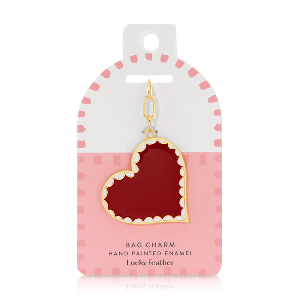 Red heart-shaped bag charm on a pink and white packaging with 'Lucky Feather' branding.