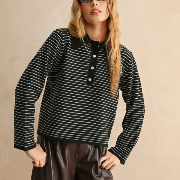 Woman wearing a black and white striped sweater with buttons on a beige background