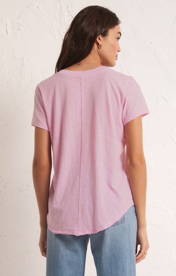 back view of model wearing the asher v neck tee. shows the raw seam going down the middle of the back. also shows the relaxed fit and the curved raw hem. 