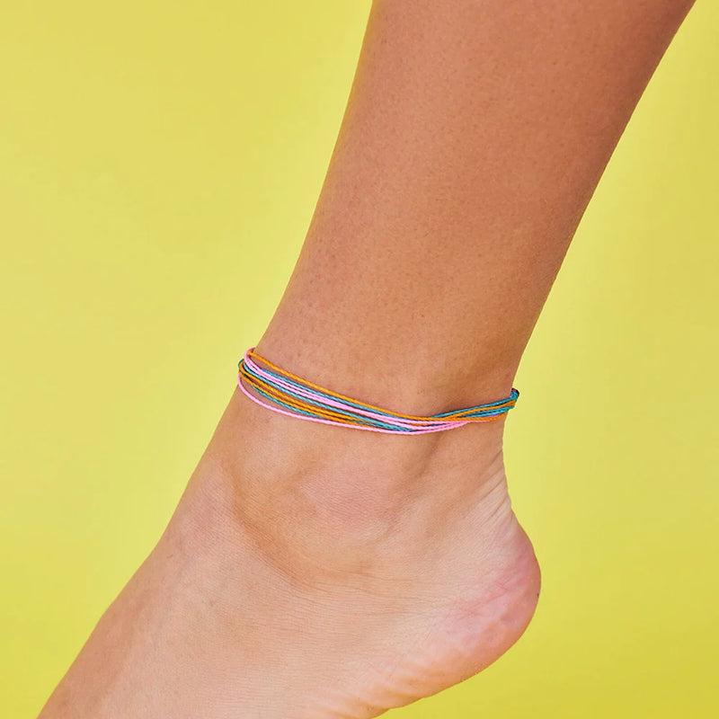 Shows a yellow backdrop with an ankle wearing an anklet made of teal, pink, and orange wax coated strings