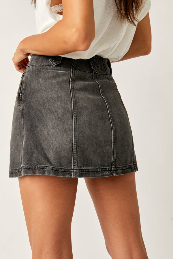 back/side view of model wearing the runaway denim skirt. shows the detailed seaming. also shows the side zipper closure, the button flaps at the waist and the a line silhouette