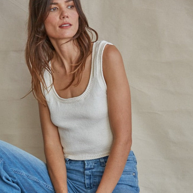 shows front view of model wearing tank top. shows the scooped neckline, sweater fabrication, cropped length and thick straps.