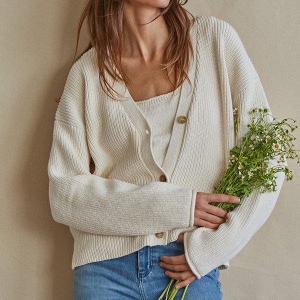 front view of model in cardigan. shows the v-neckline, dropped shoulders, buttons down the front and boxy oversized fit.