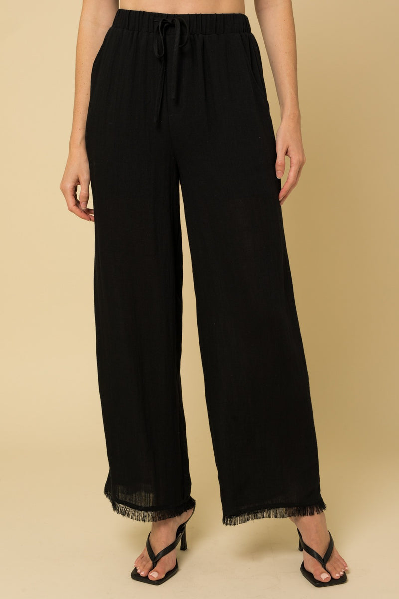 Shows front view with elastic waistband, tie drawstring, and fringe hem.