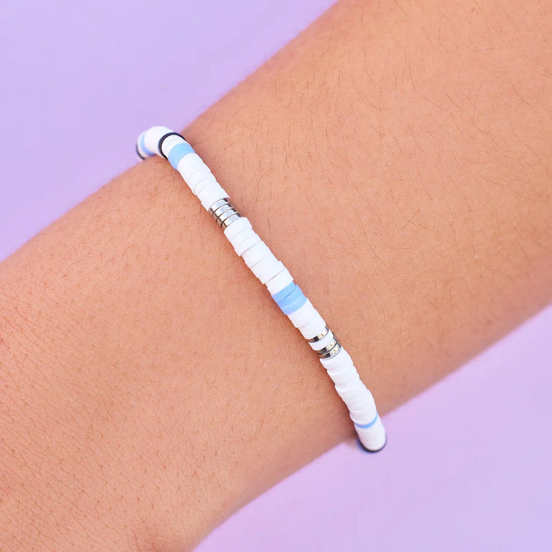Model is wearing wax-coated string and vinyl heshi bead disc bracelet. Has white, blue and silver beads.