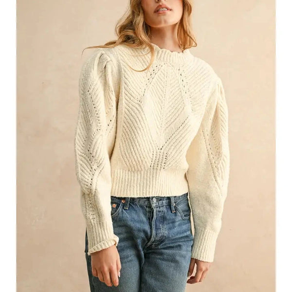 shows model wearing the beige sweater with puff sleeves and scalloped detailing. 