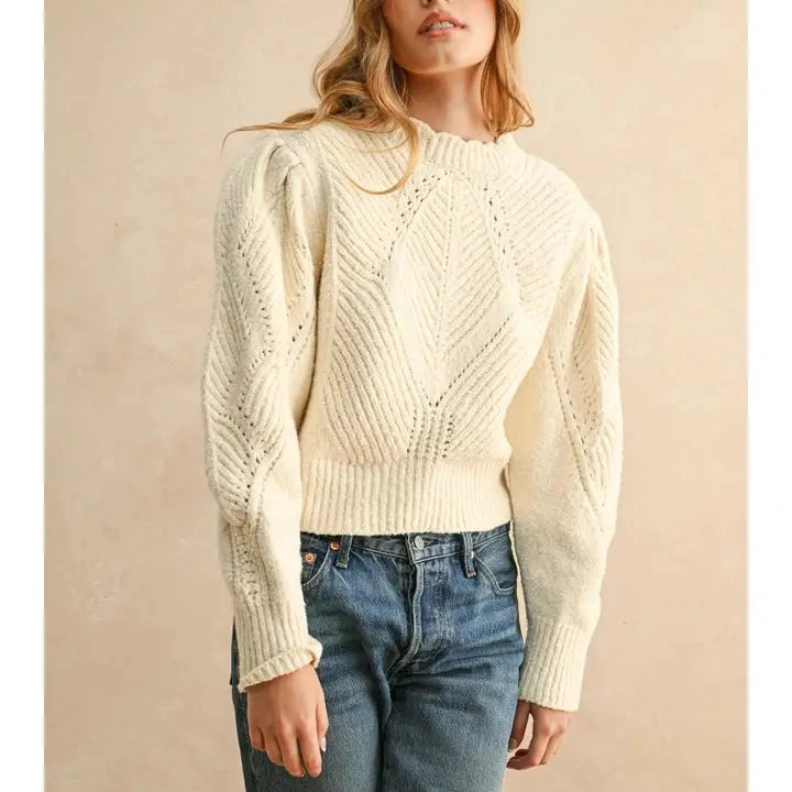 shows model wearing the beige sweater with puff sleeves and scalloped detailing. 