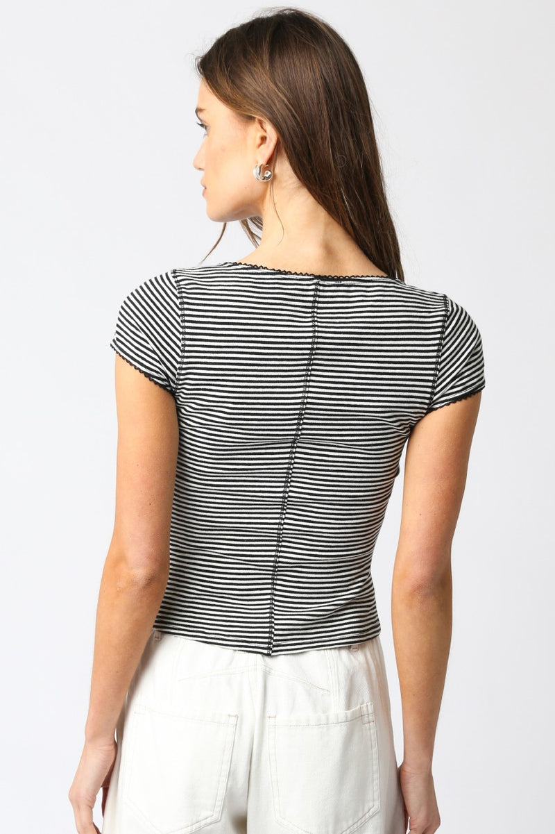 back view of the model wearing the tahni top. shows the stripe pattern. also shows the fitted style, the lace trim 