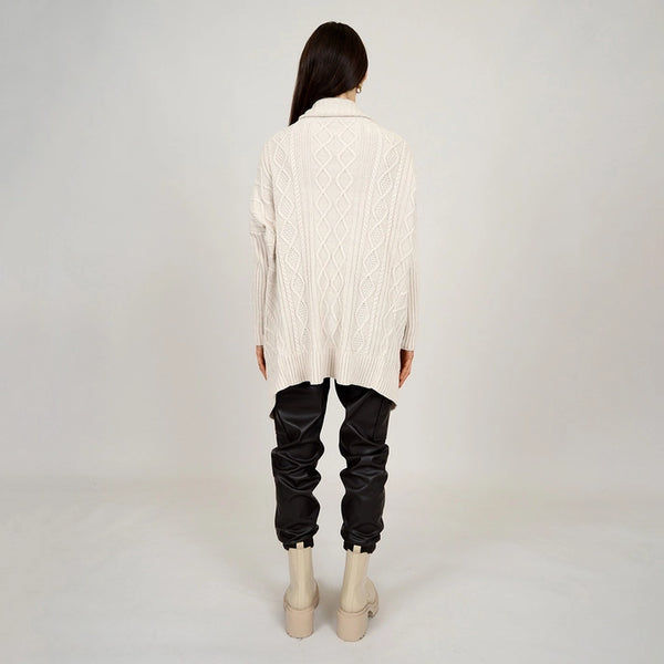 back view of model in cardigan. shows an overzied fit, dropped shoulders and cable knit fabrication.