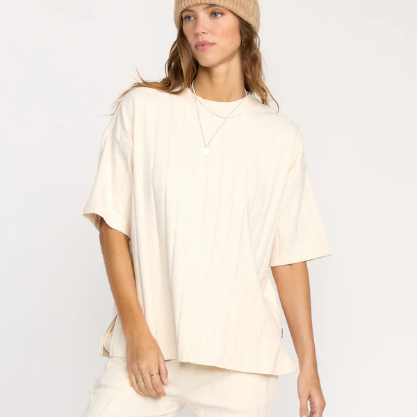 Woman wearing a beige beanie and matching outfit on a white background