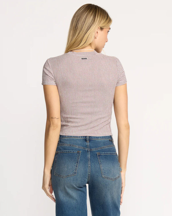 Woman wearing a checkered shirt and blue jeans on a light gray background
