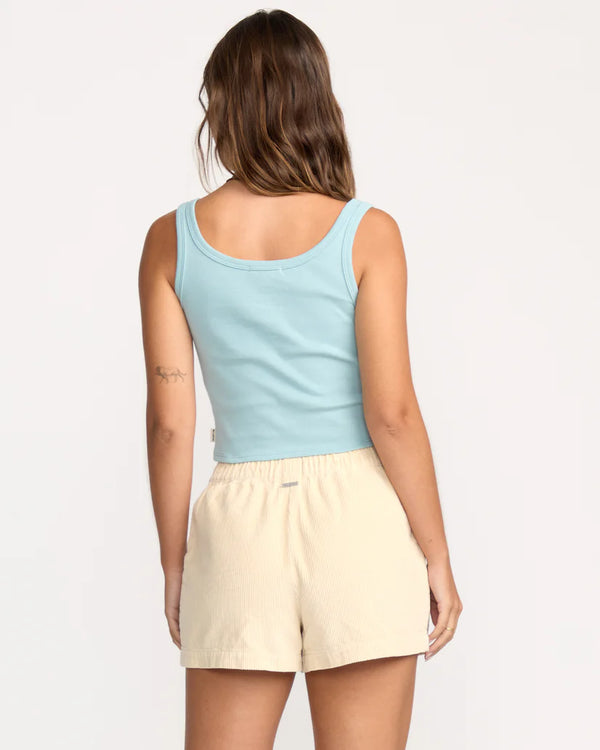 Woman wearing a light blue tank top and beige shorts on a white background
