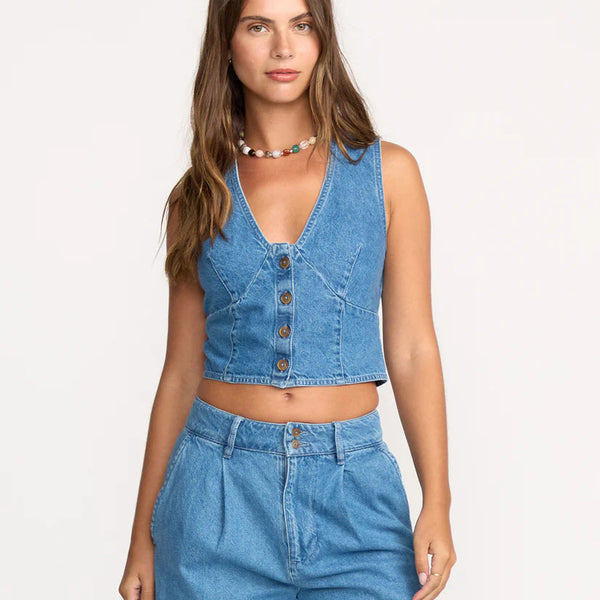Woman wearing a blue denim crop top and high-waisted jeans on a white background