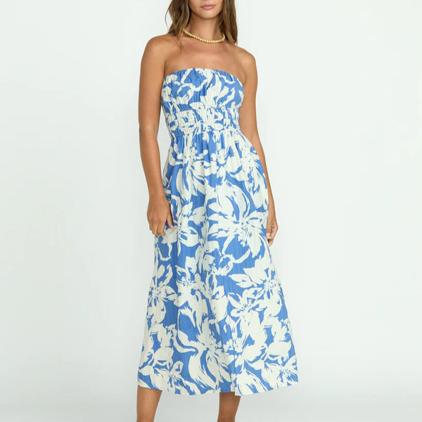 front view of the model wearing the in the sky midi dress. shows that the dress is strapless. also shows the elastic waist, the midi length and the white and blue floral pattern. 