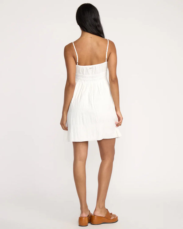 Woman wearing a white dress with thin straps on a plain background