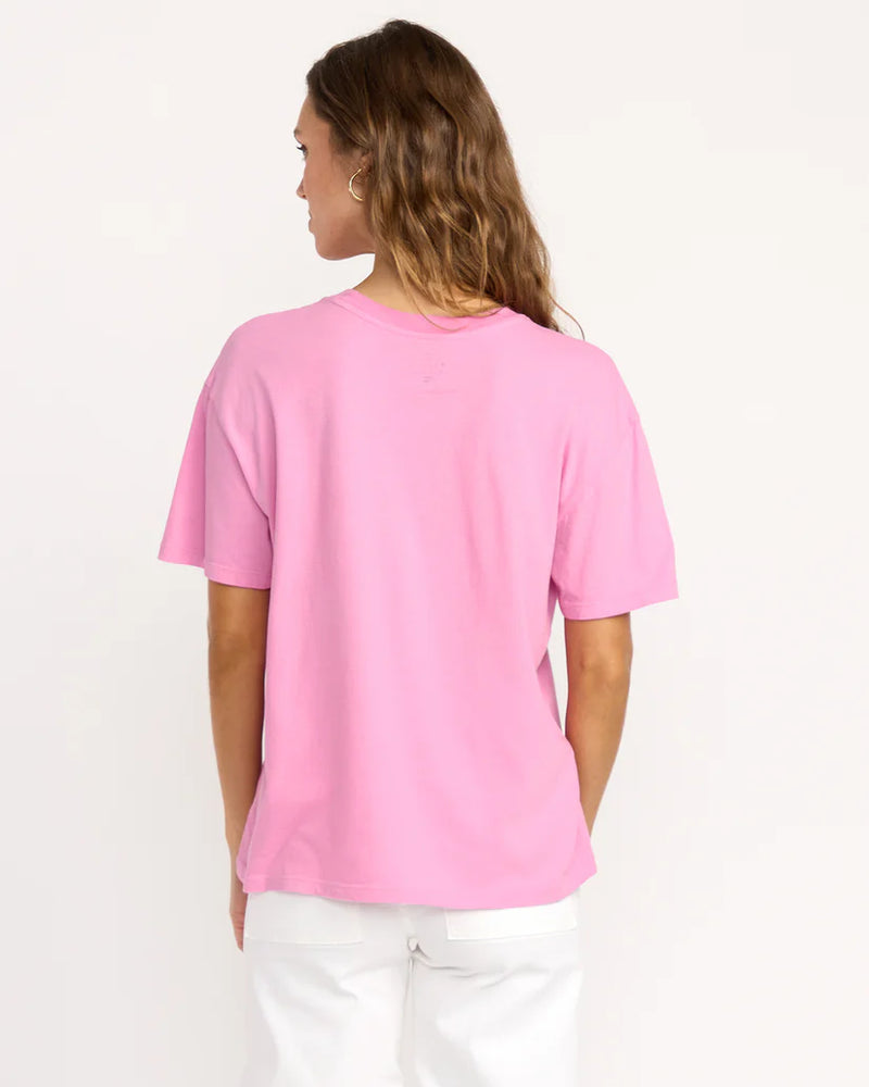 back view of the model wearing the bright new day tee. shows the crew neckline. also shows the relaxed fit, the pink and the short sleeves. 