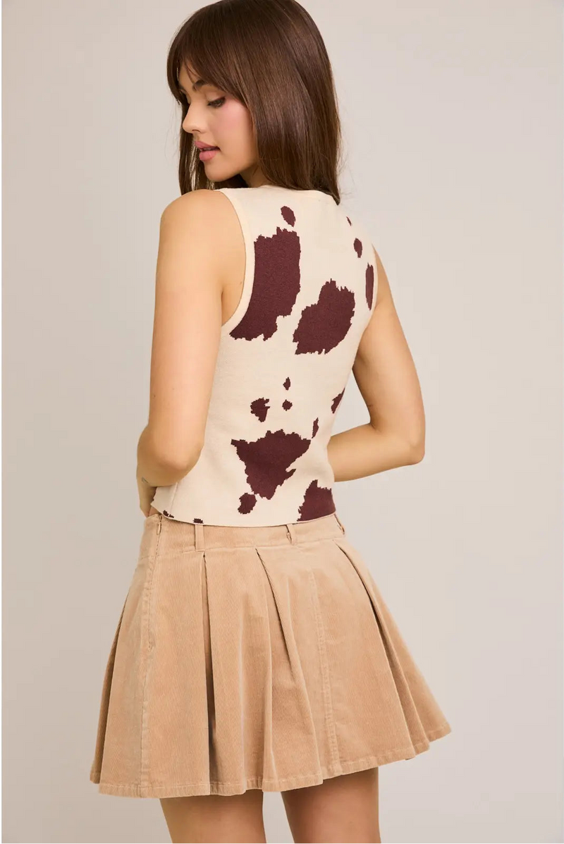 back/side view of the model wearing the bessie sleeveless sweater. shows the animal print. also shows the colors of beige and brown, the waist length, and that it is sleeveless 