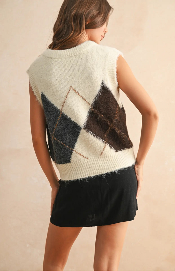 Woman wearing a sleeveless, patterned sweater with a neutral background