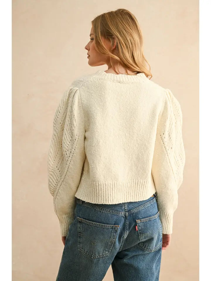 shows the back view of the model wearing the beige sweater with puff sleeves slim fit and scalloped detailing. 