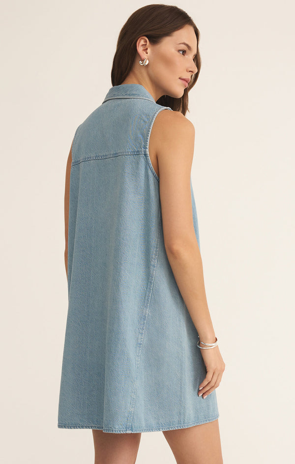 back view of the model wearing the new day twill mini dress. shows the back stitching. also shows the collar, the light wash denim and that it is sleeveless. 