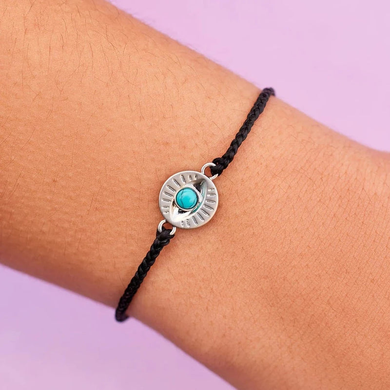 Shows a mini braided wax coated bracelet with a circular eye charm with turquoise center stone.