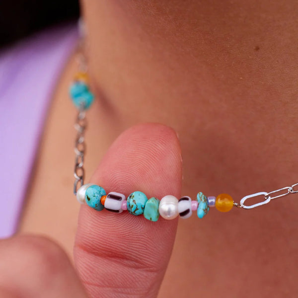 A close up of the rose quartz, turquoise, pearl and yellow quartz stones clusters on the paperclip chain.